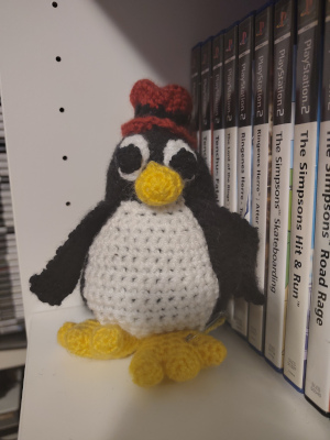 A knitted penguin with a red heat, taken with Android's default camera app.